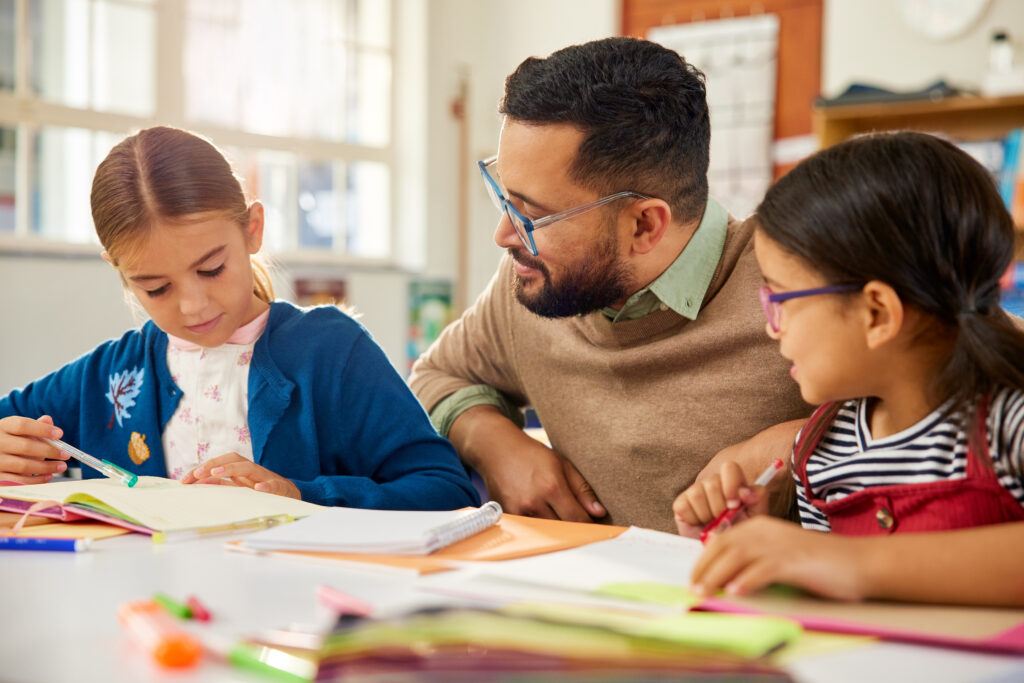 Male teacher working with two female students showing individualized care in educational services