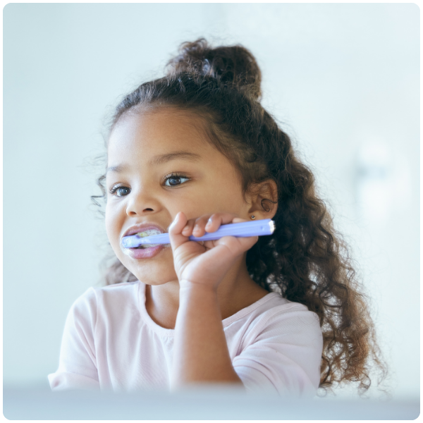 Girl brushing her teeth in mirror practicing skills and integrated services learned at Spiritos School