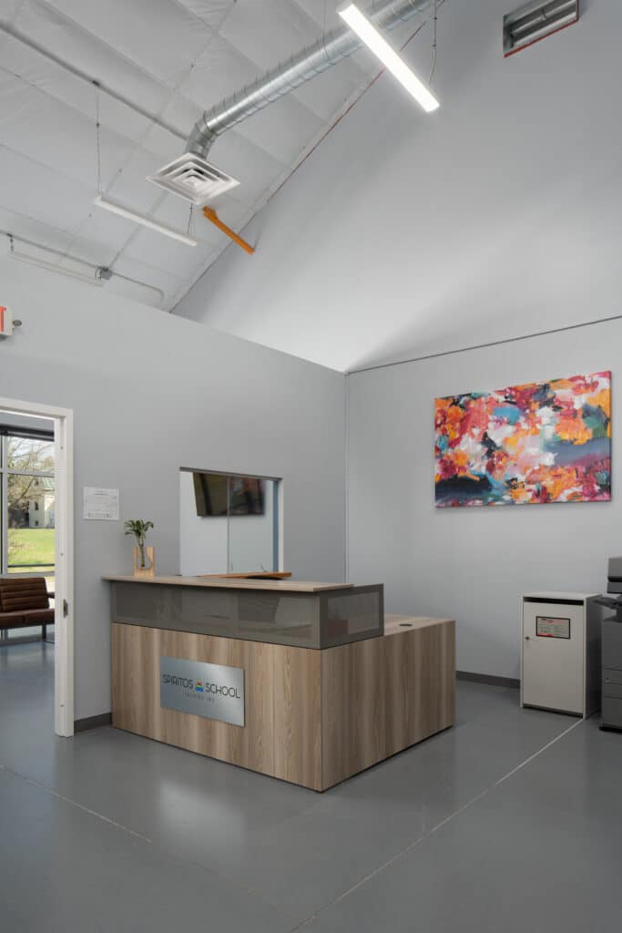 reception desk at Spiritos School entrance with colorful artwork on wall