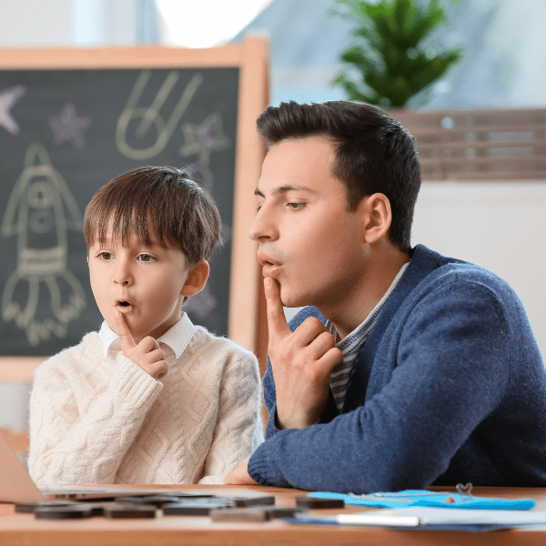 boy and teacher practicing sounding out letters for speech therapy 